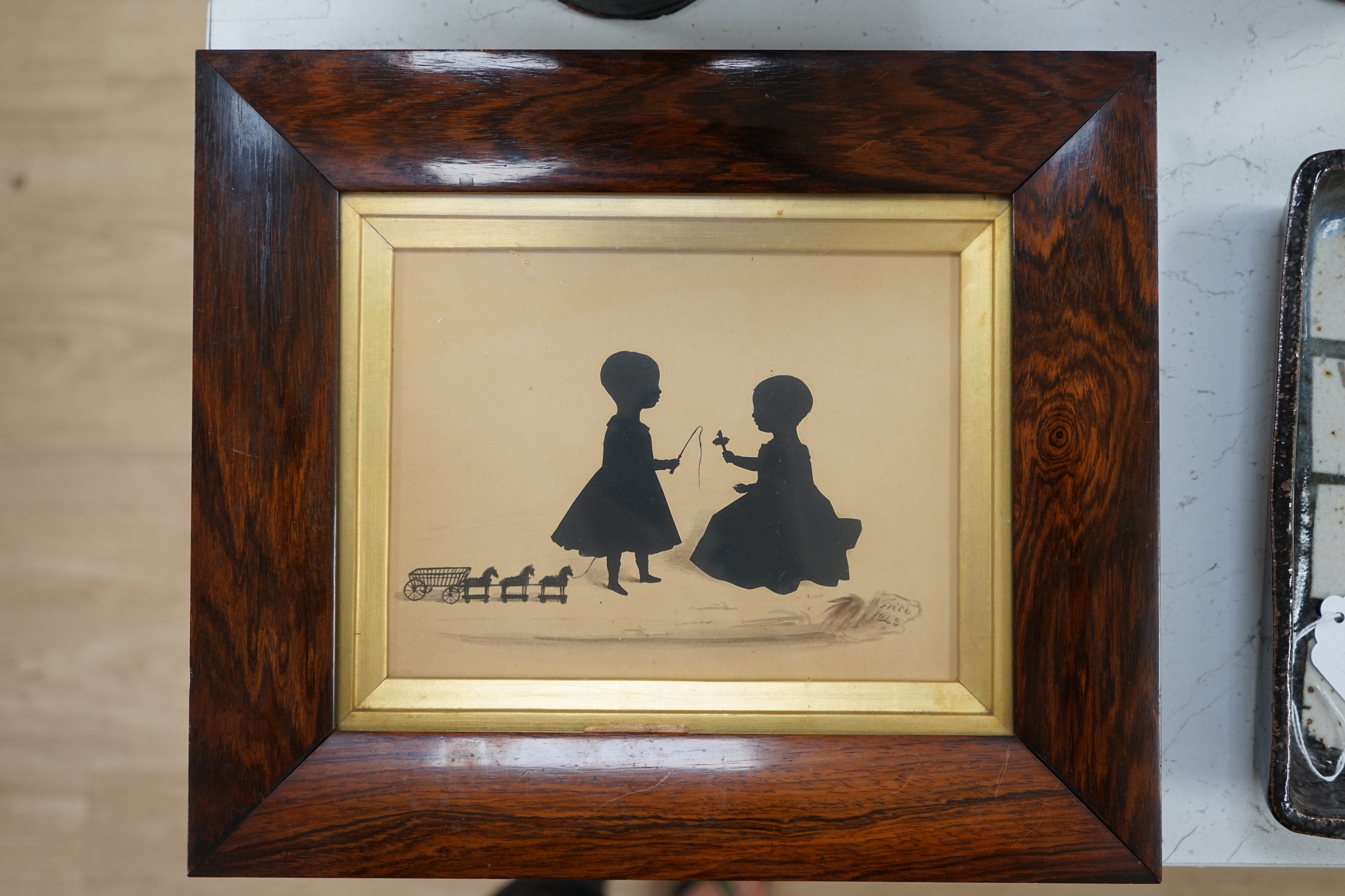 Frederick Frith (1819-1871), hand painted silhouette, Children playing with a spinning top and a toy horse drawn carriage, signed and dated 1843, 15 x 19.5cm. Condition - fair